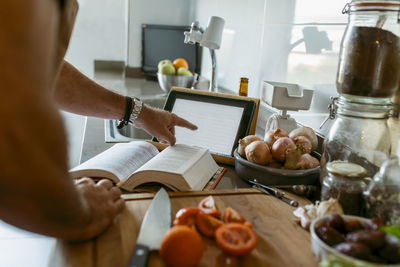 Cropped image of human hand using digital tablet in kitchen