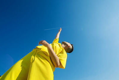 Low angle view of young man holding blue sky
