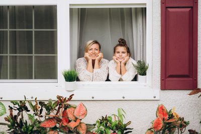 Portrait of woman and girl sitting on window