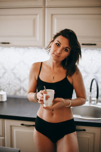 Portrait of young woman standing at home