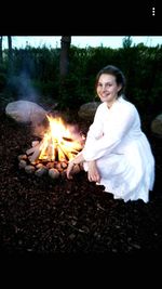 Portrait of smiling young woman sitting on bonfire