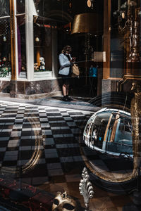 Reflection of man walking in city street