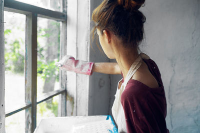 Side view of young woman painting wall