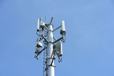 Low angle view of communications tower against blue sky