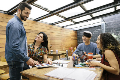 Young man working with woman sitting in office