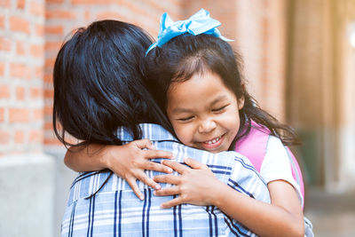 Smiling girl embracing mother outdoors