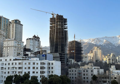 Buildings in city against clear blue sky