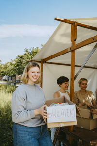 Portrait of happy volunteer holding sweater box during charity drive at community center