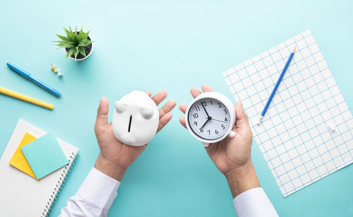 Digital composite image of hand holding clock over white background