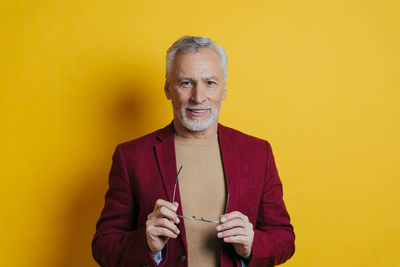 Portrait of smiling man standing against yellow background