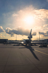 Airplane on airport runway against sky during sunset