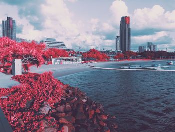View of city buildings by sea against sky