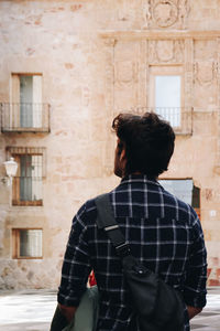 Rear view of woman standing against building