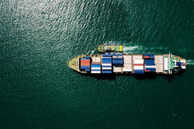 Aerial top view container ship sailing on the green sea full speed container for logistics, 