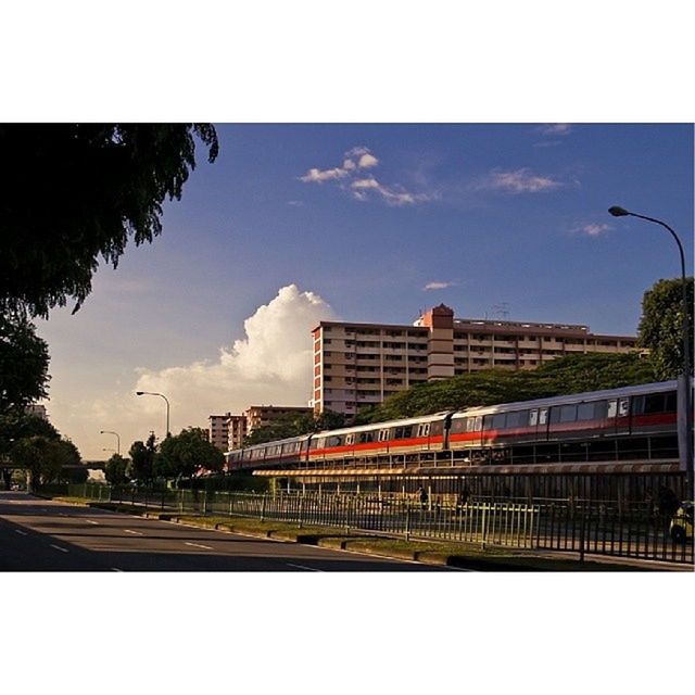 transportation, transfer print, sky, railroad track, building exterior, architecture, built structure, rail transportation, mode of transport, public transportation, land vehicle, auto post production filter, car, train - vehicle, road, railroad station platform, city, railroad station, street, cloud - sky