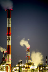 Low angle view of illuminated factory against sky at night