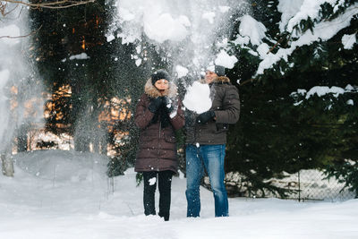 Woman standing on snow covered tree during winter