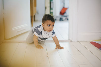 Toddler looking away while crawling on floor at home