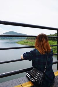 Rear view of woman looking at river against sky