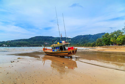 Boat moored on beach against sky