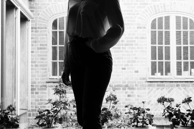 Midsection of woman standing by window of building