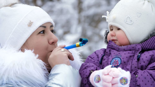 Against the background of the winter forest, a young woman, mom holds on her hands