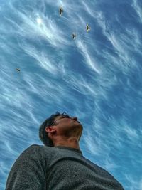 Low angle view of man looking up against blue sky