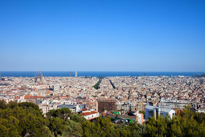 High angle view of town by sea against clear blue sky