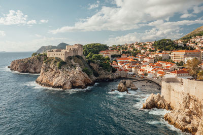 Scenic view of sea by mountain against sky