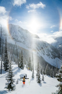 Skier riding towards sun halo / sun dog during heli skiing session in the kootenays, kaslo, b.c.