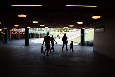 Silhouette people walking in illuminated corridor