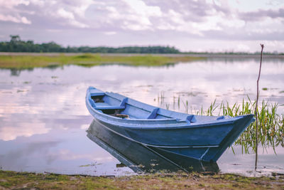 Boat moored at lakeshore against sky