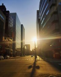 City street amidst buildings against sky during sunset