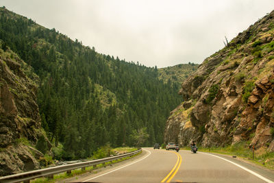 Road amidst trees against sky