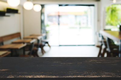 Empty chairs and table by window in building