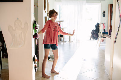 Barefoot teen girl stands inside her home and poses awkwardly