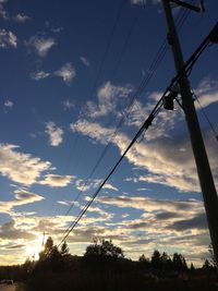 Low angle view of electricity pylon against cloudy sky