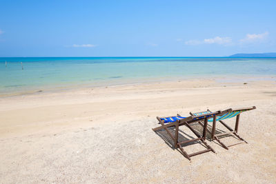 Deck chairs on beach against sky