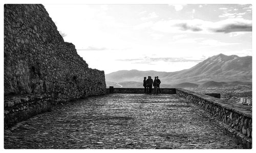 People walking on mountain road against sky