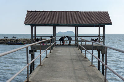 Rear view of pier on sea against sky