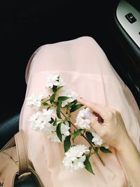 Midsection of woman holding flowers while sitting in car