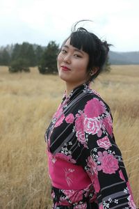 Portrait of young woman in kimono standing on field