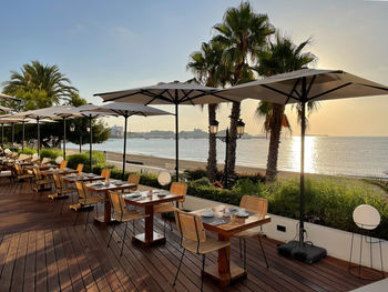 Chairs and tables at swimming pool by sea against sky