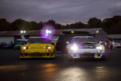 Vehicles on road against sky at night