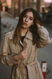 Portrait of young woman standing on footpath