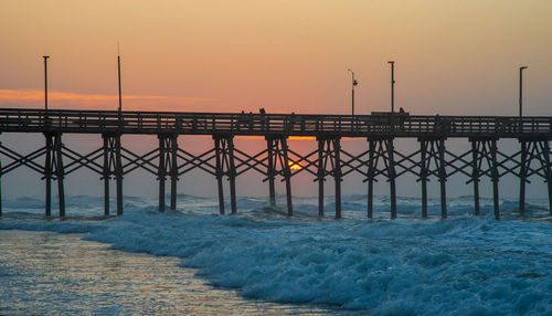 Pier over sea against sky during sunrise