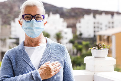 Portrait of man holding eyeglasses standing outdoors