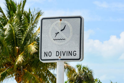 Low angle view of road sign against blue sky