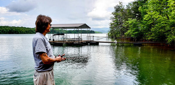 Man standing by lake against sky