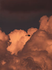 Low angle view of airplane flying in sky during sunset